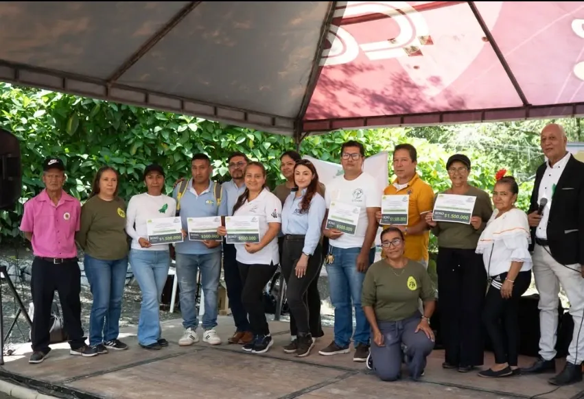 Personas posan bajo una carpa sosteniendo bonos de estímulo.