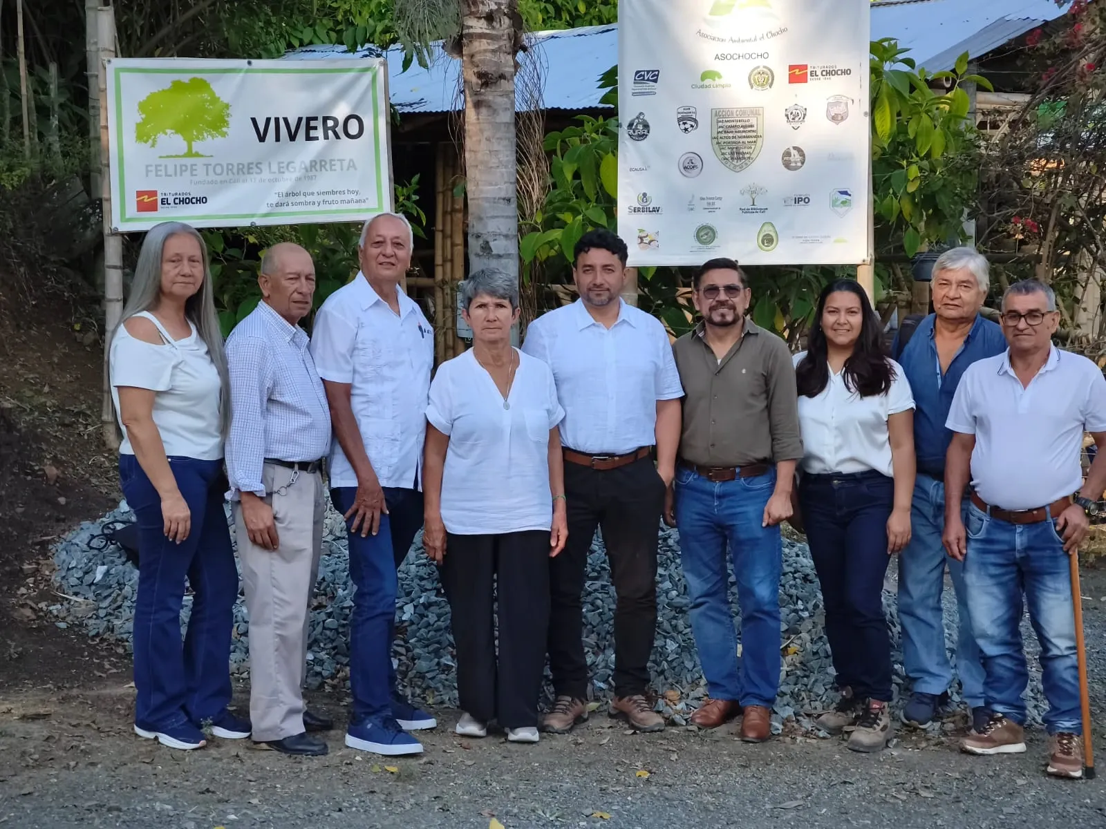 Nueve personas posan frente al letrero del vivero Felipe Torres Legarreta y al pendón de la Asociación Ambiental El Chocho, cubierto de logos de organizaciones.
