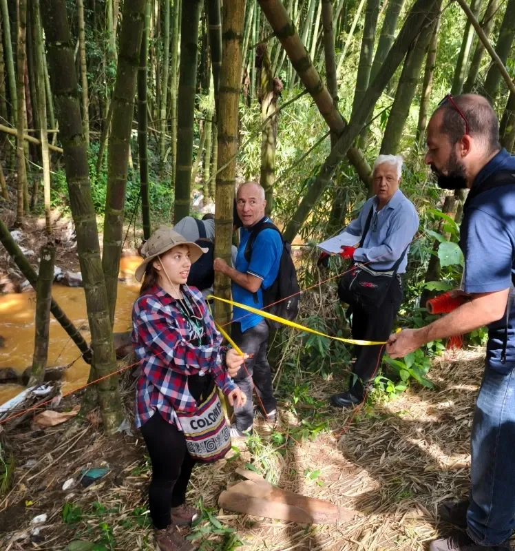 Participantes extienden una cinta métrica entre guaduas a orillas de la quebrada.