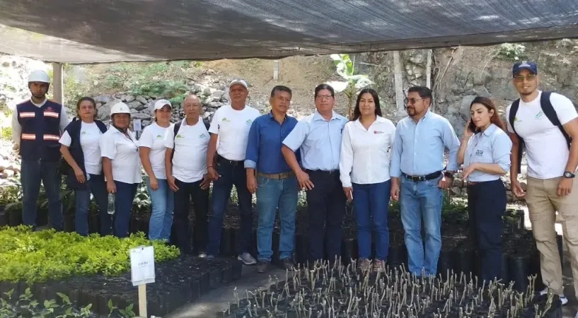 Un grupo de personas posa en el vivero entre plántulas en bolsa.